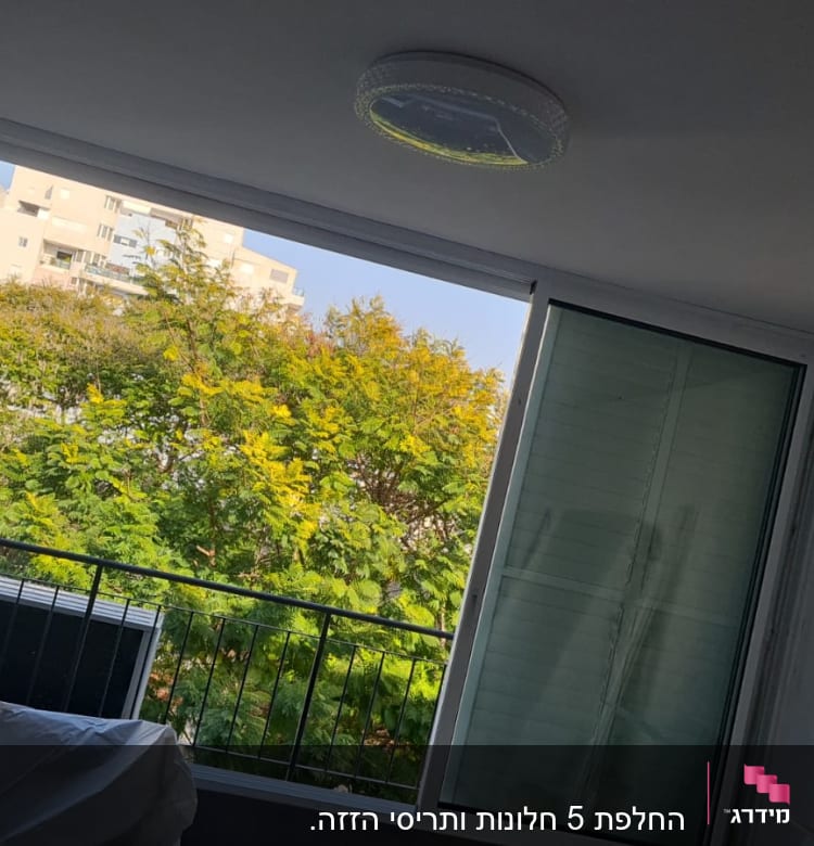 חלון אלומיניום פתוח עם תריסים ירוקים